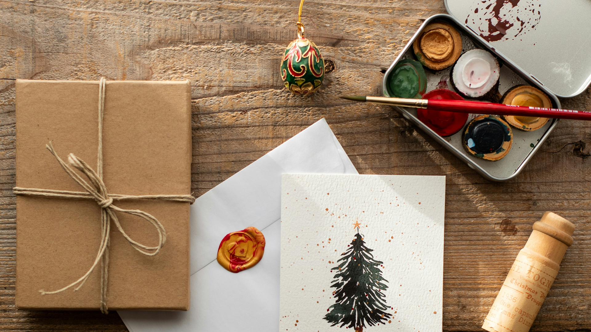 A photograph of Christmas cards, a present, and watercolour paint.
