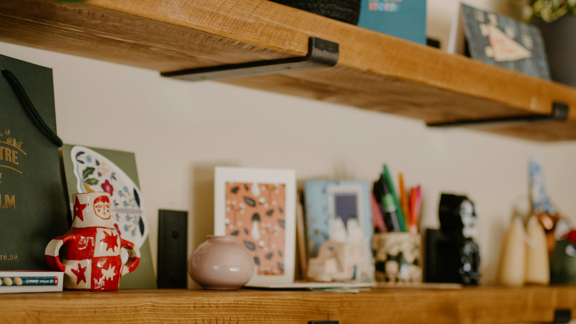 Photograph of a shelf with cards and pens and ornaments on