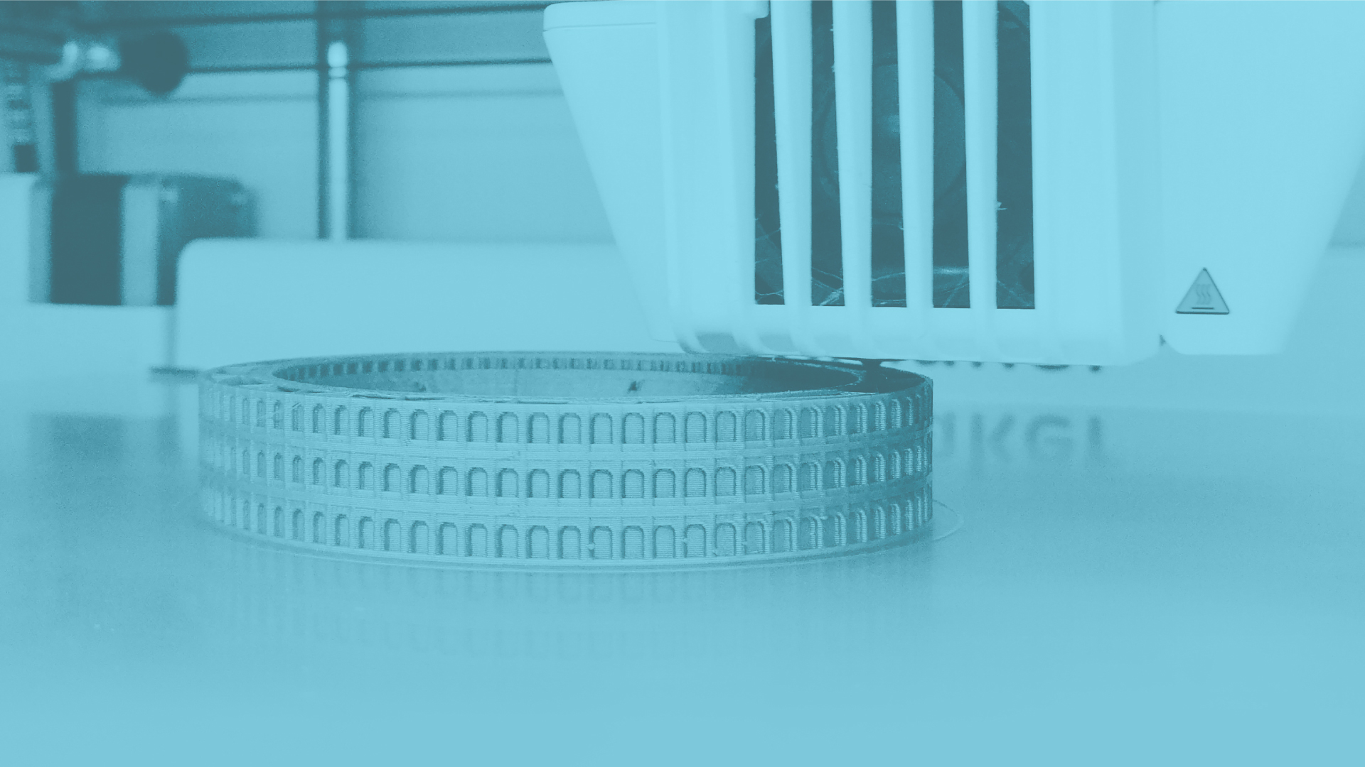 Close-up of a 3D printer printing a circular object on the build plate.