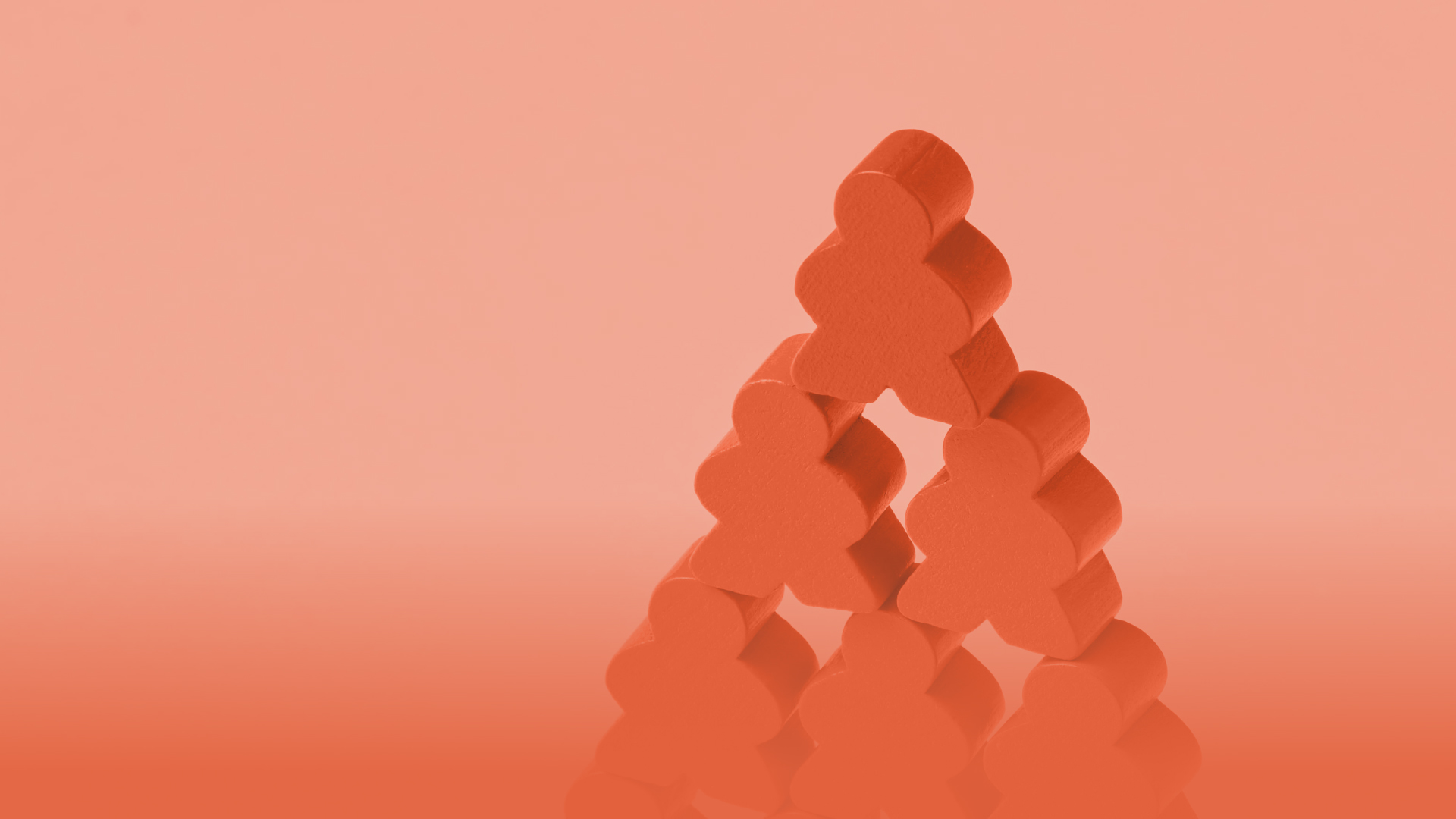 Stack of orange wooden figures arranged in a pyramid shape on a peach background.