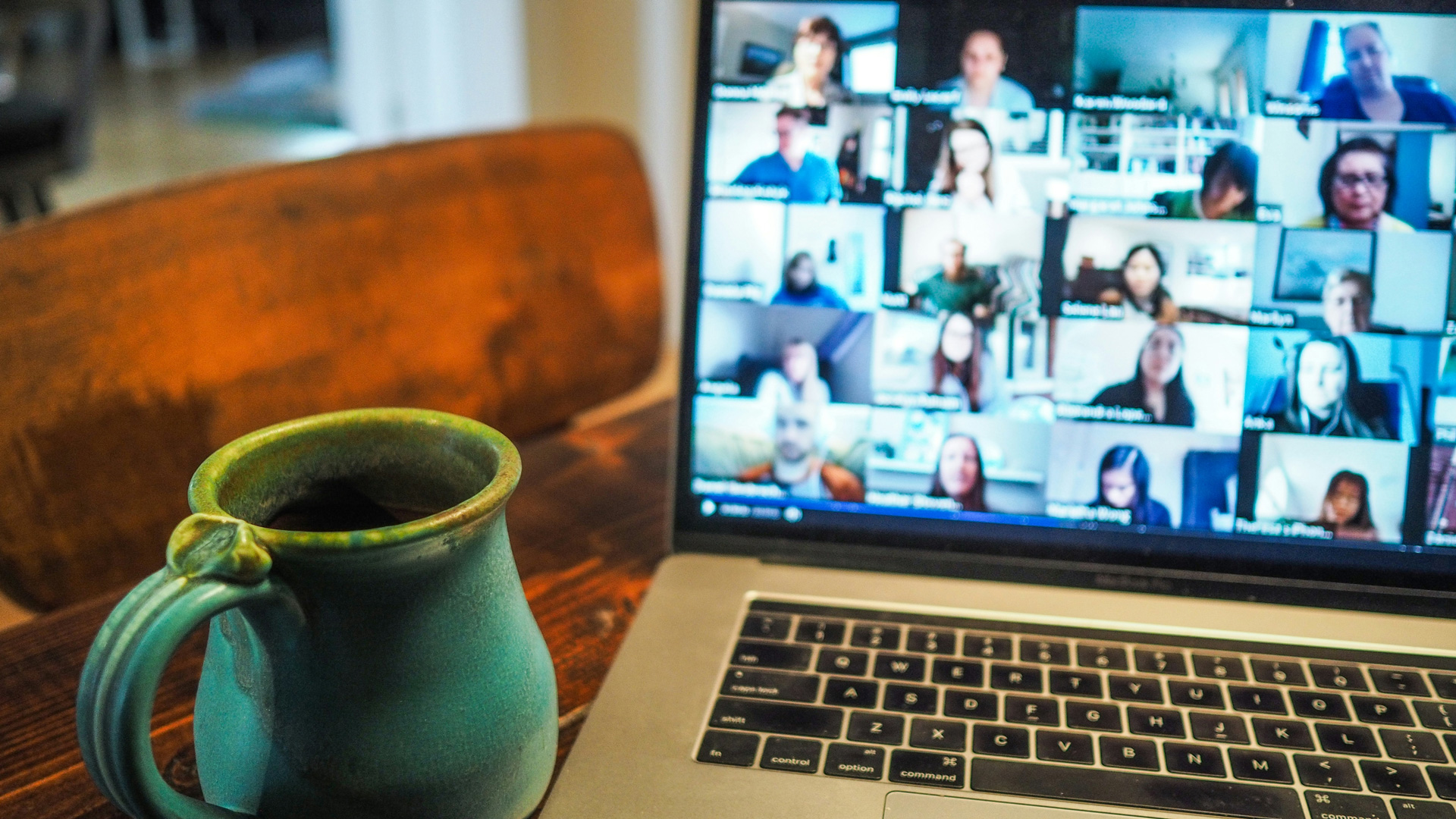 Photograph of a video call on a laptop screen with a mug of coffee placed next to it.