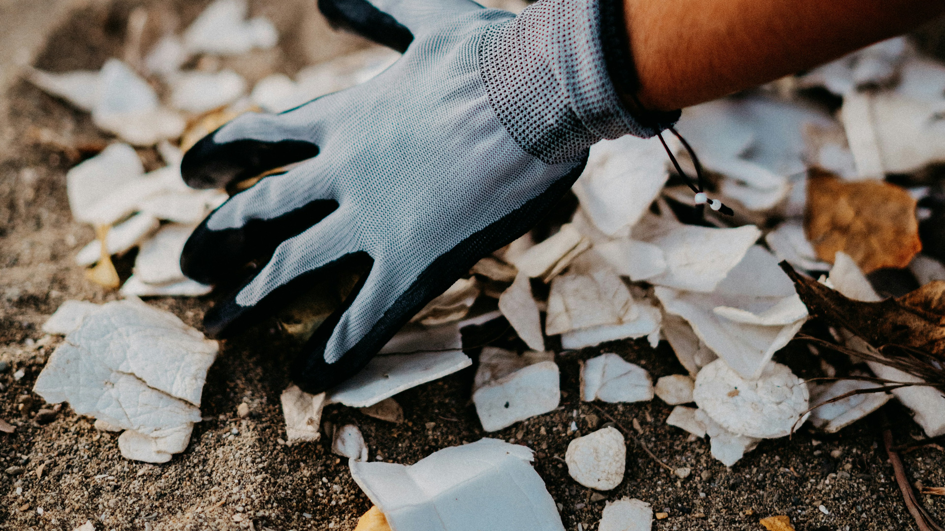 A hand with a glove one sorting our waste.