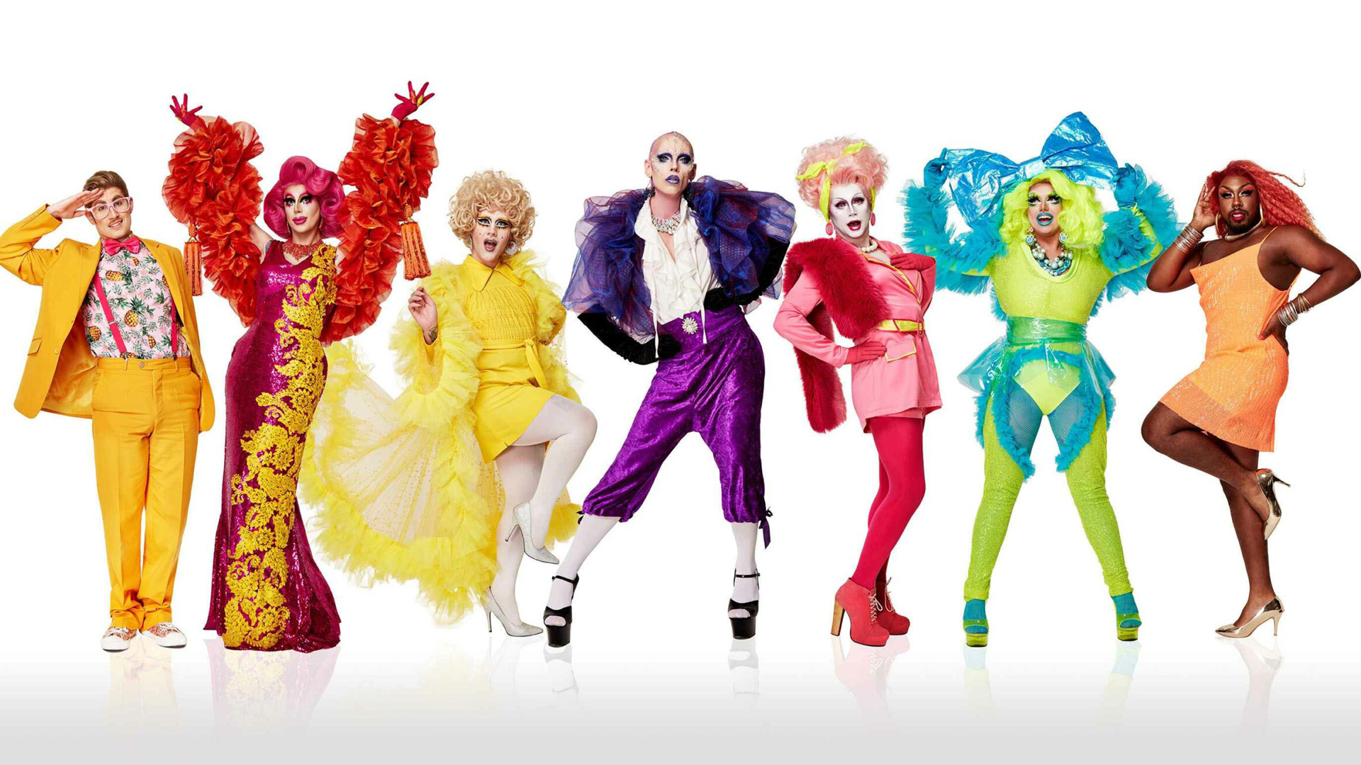 Seven people wearing colourful costumes stand in a row against a white background.