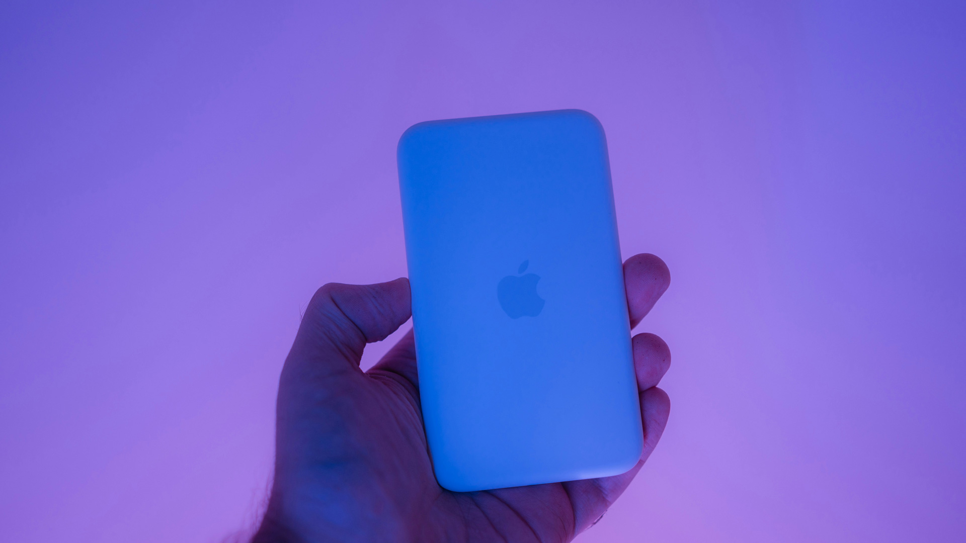Image of a hand holding a blue phone on a purple background.