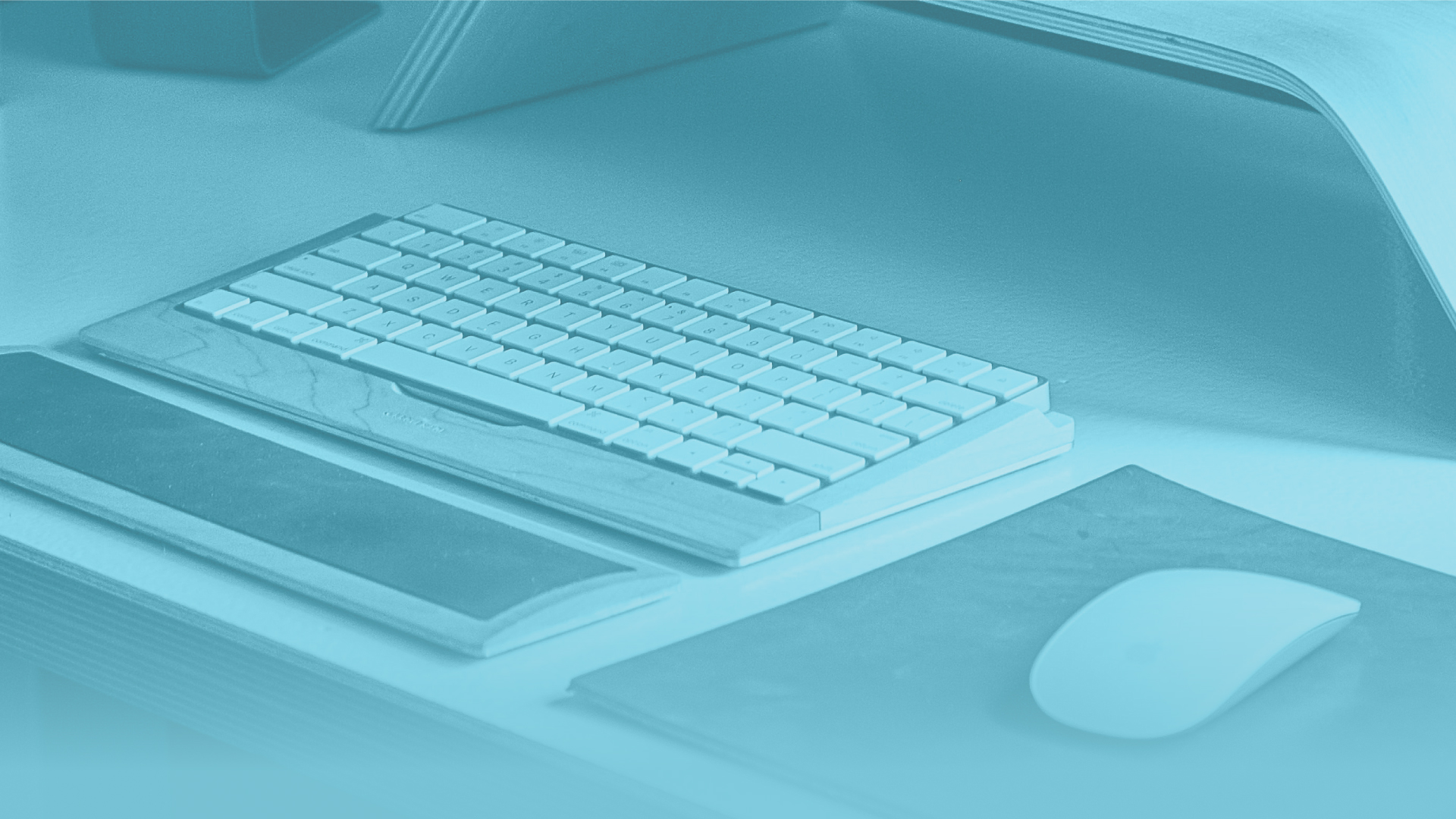 Close-up of a minimalist desk setup with a keyboard, mouse and tablet.