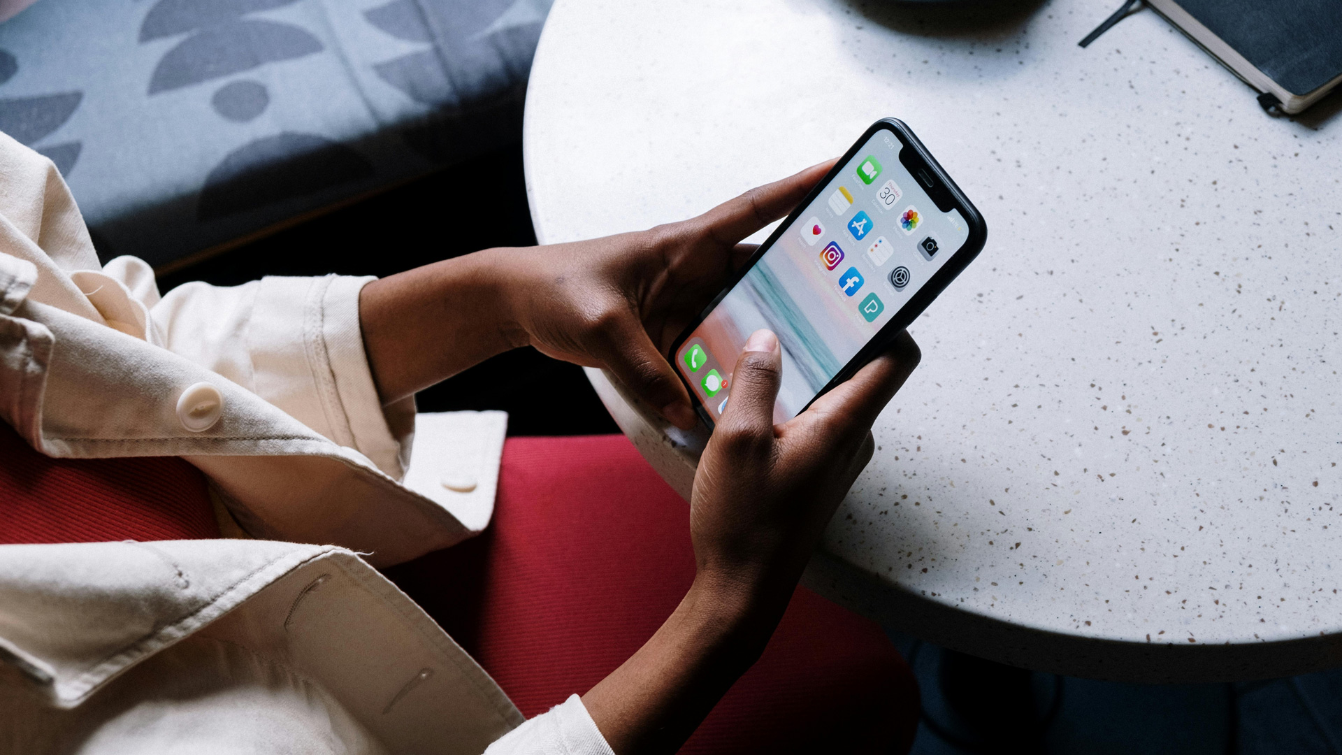 Photograph of someone holding a phone on a table.