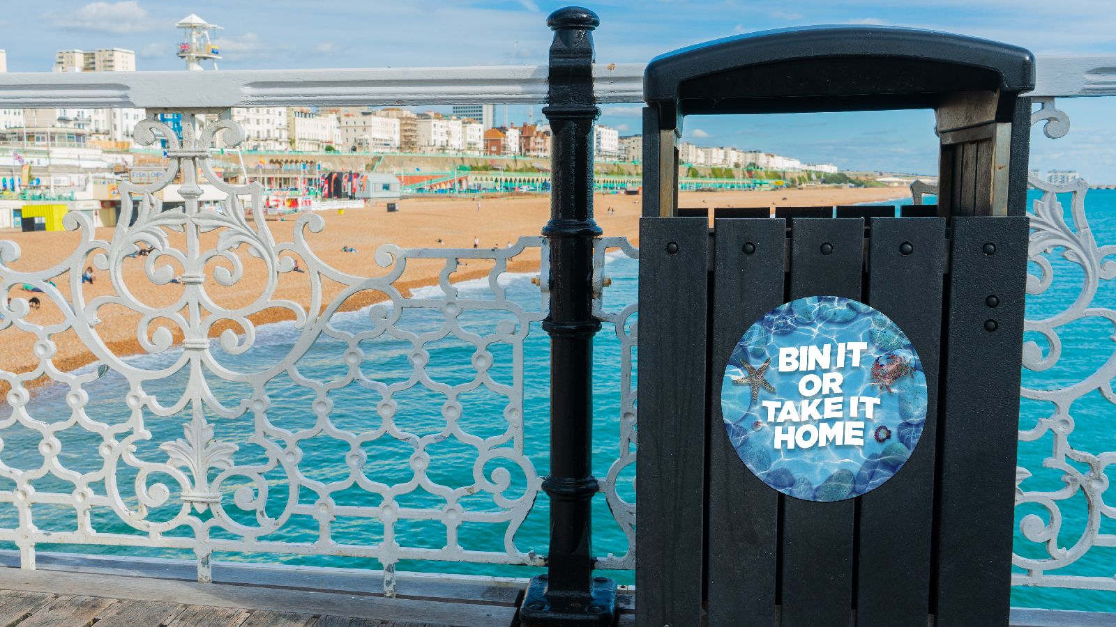 A marine scene with the words 'Bin it or take it home' on it stuck on a bin.