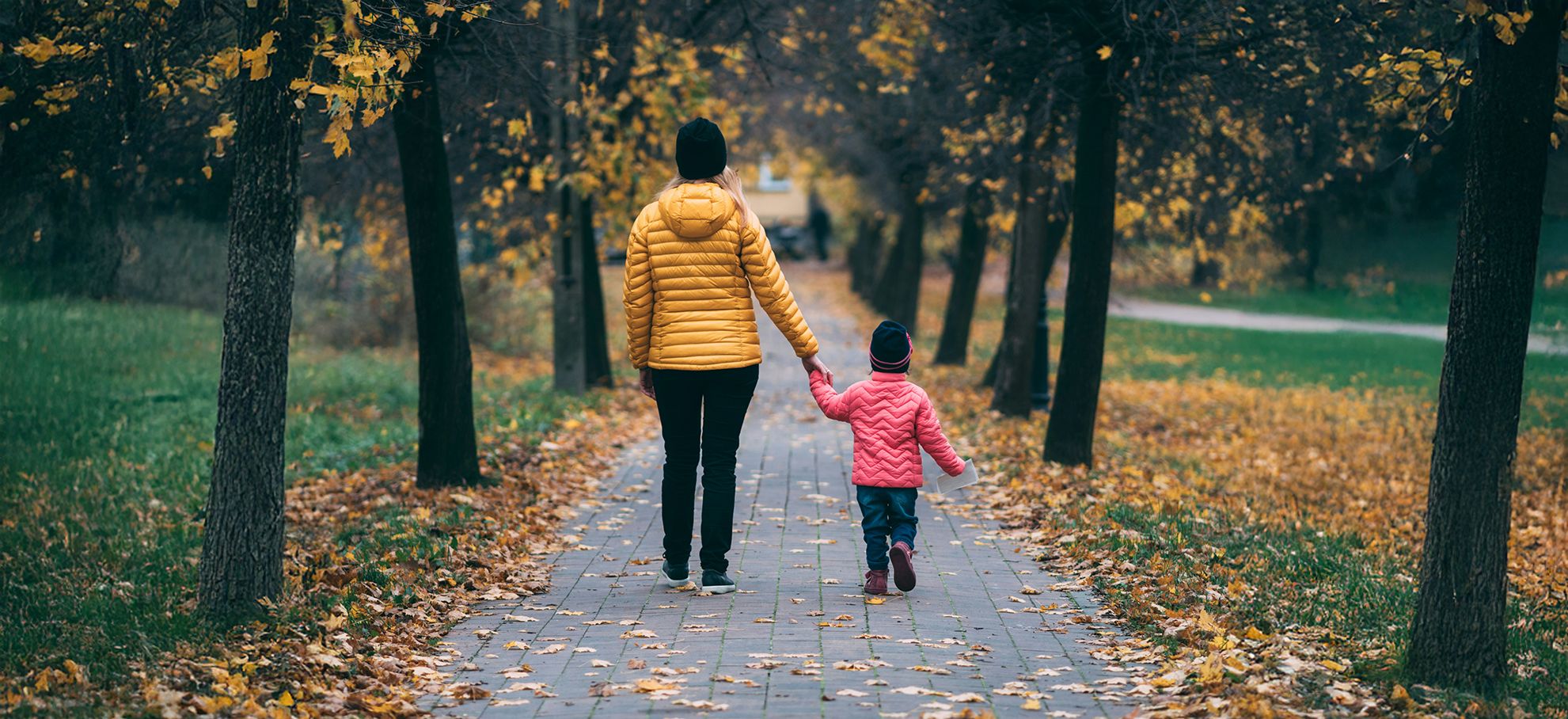 A woman and child walking thtrough trees.