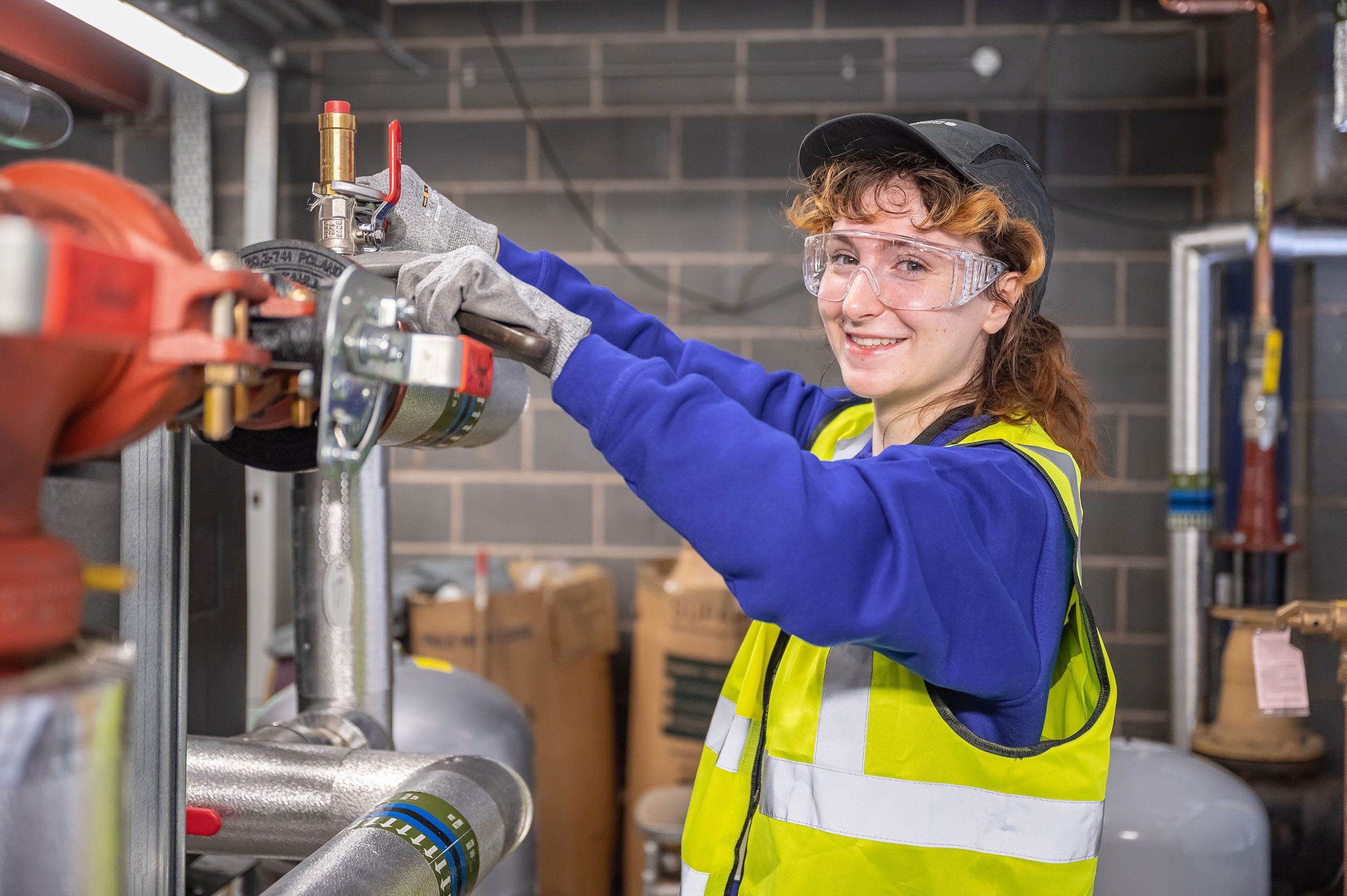 Photography of a woman working in engineering, smiling at the camera whilst fixing something.