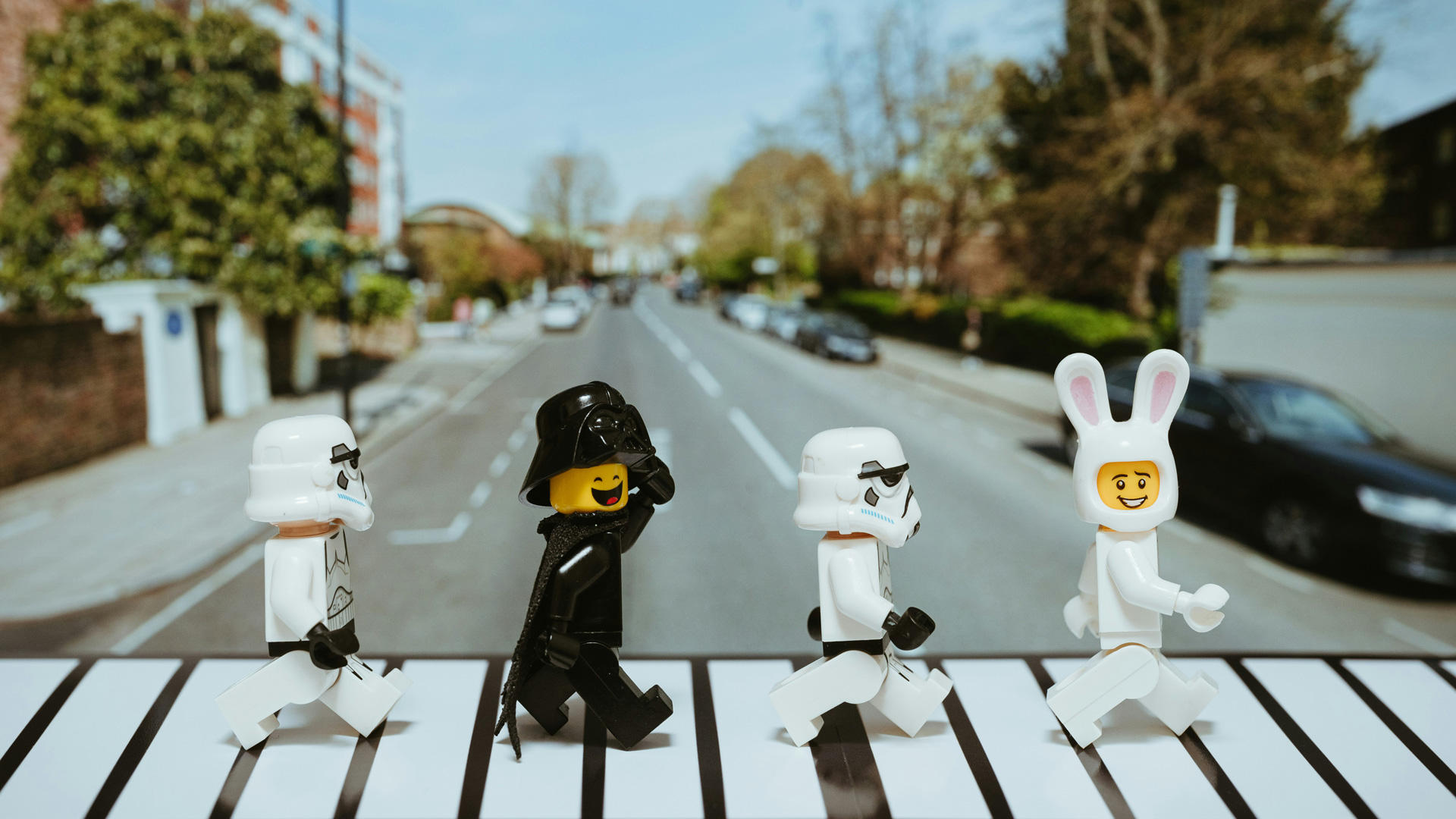 Four lego characters walking across a zebra crossing.